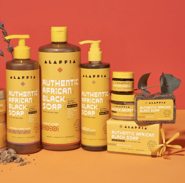 yellow bottles and pots of alaffia skincare products on an orange red background, one of the best clean beauty brands